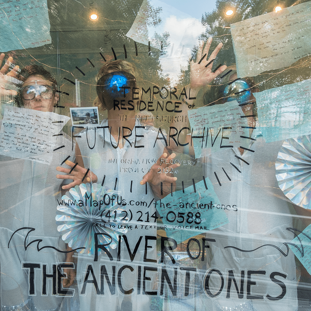 Artist Lindsey Scherloum and two assistants pose behind the window of the PCC Studio during the artist's residency in 2021