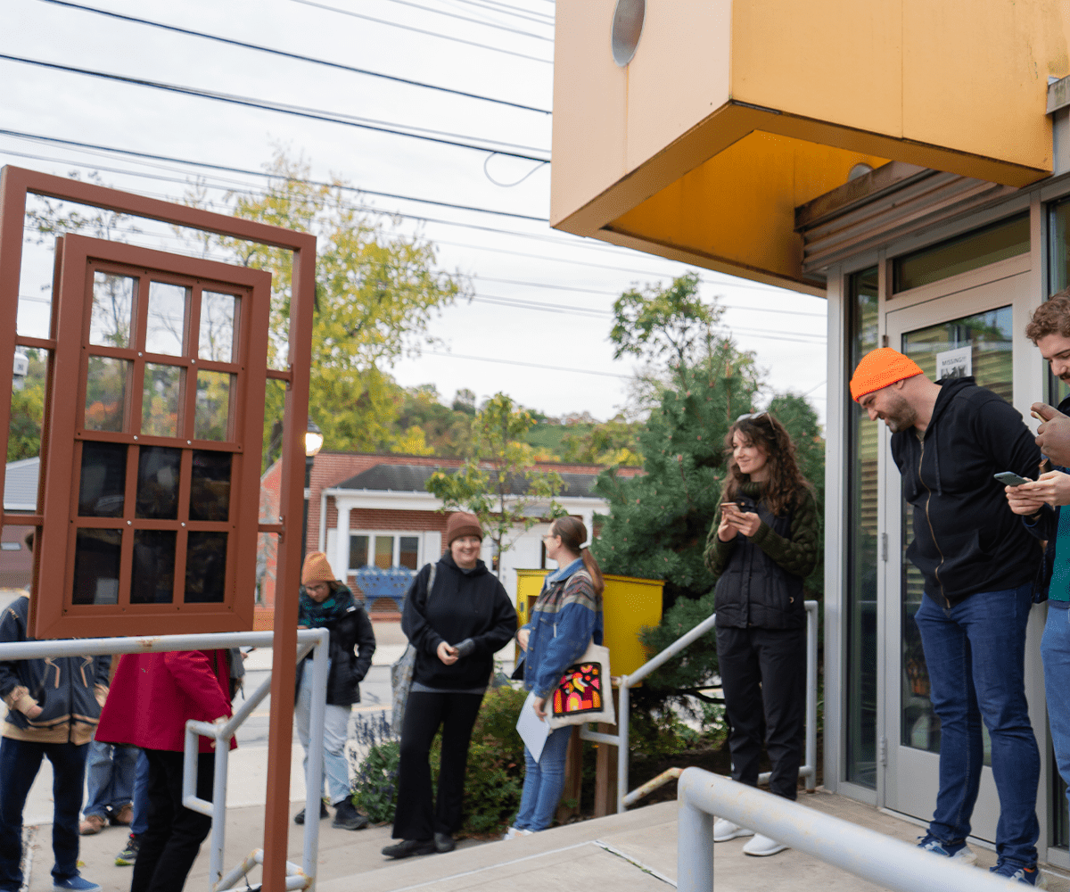 Participants of the Art Creep and Crawl Tour are gathered around the We Are Windows installation in Sharpsburg.